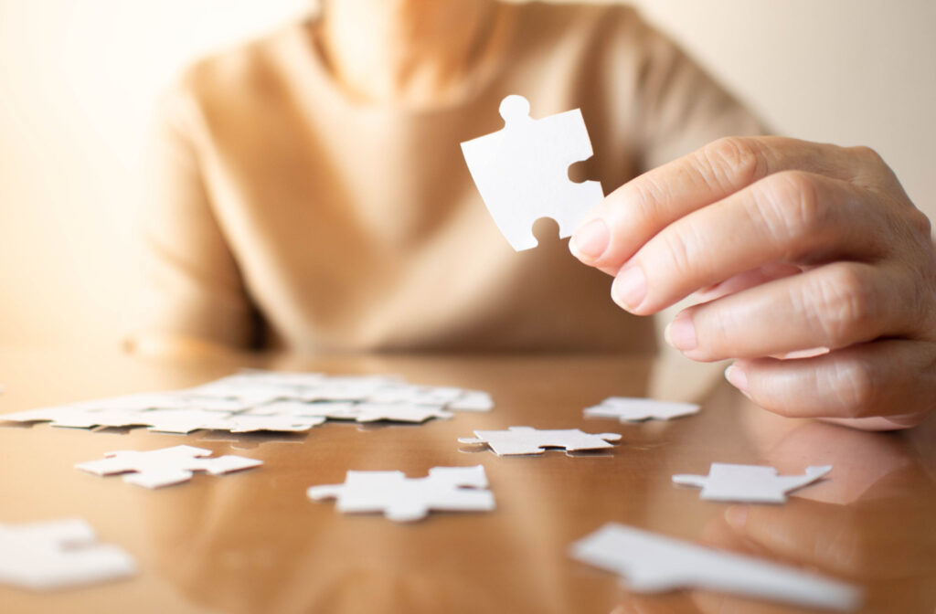 A woman putting puzzle pieces together on a table.
