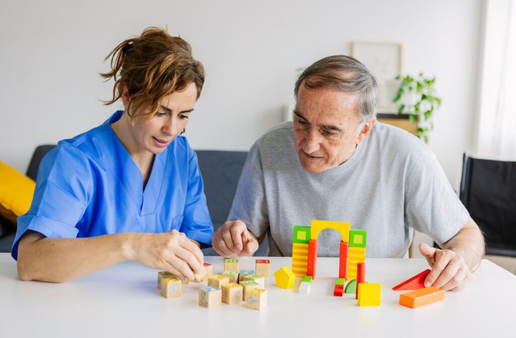A person with dementia working with building blocks as part of their cognitive therapy with a memory care staff member.