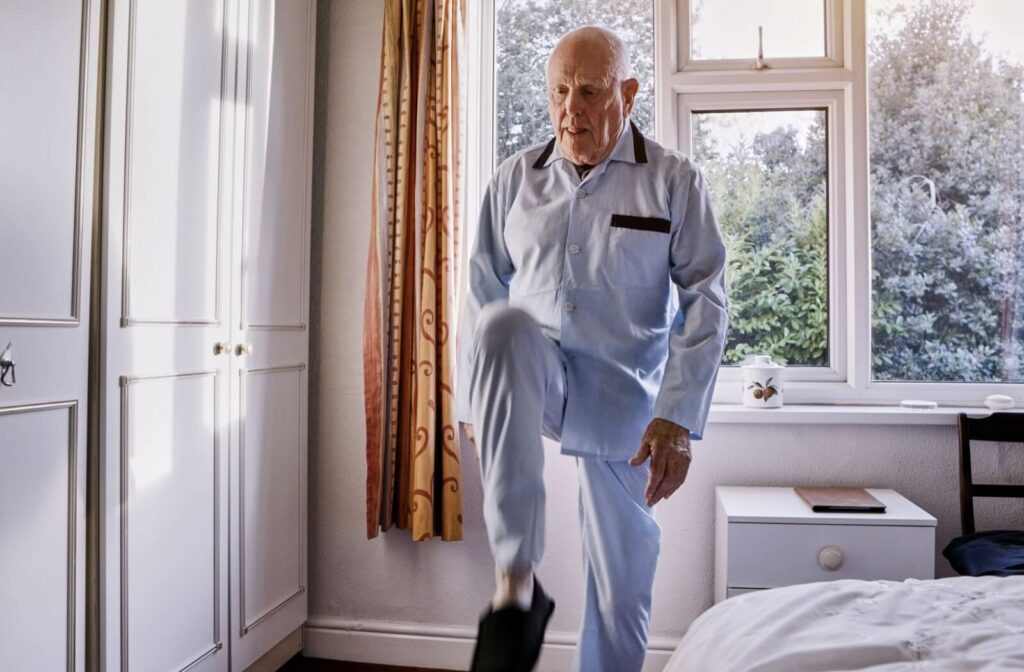A senior in pajamas performs a standing marching leg exercise first thing in the morning to warm up their leg muscles