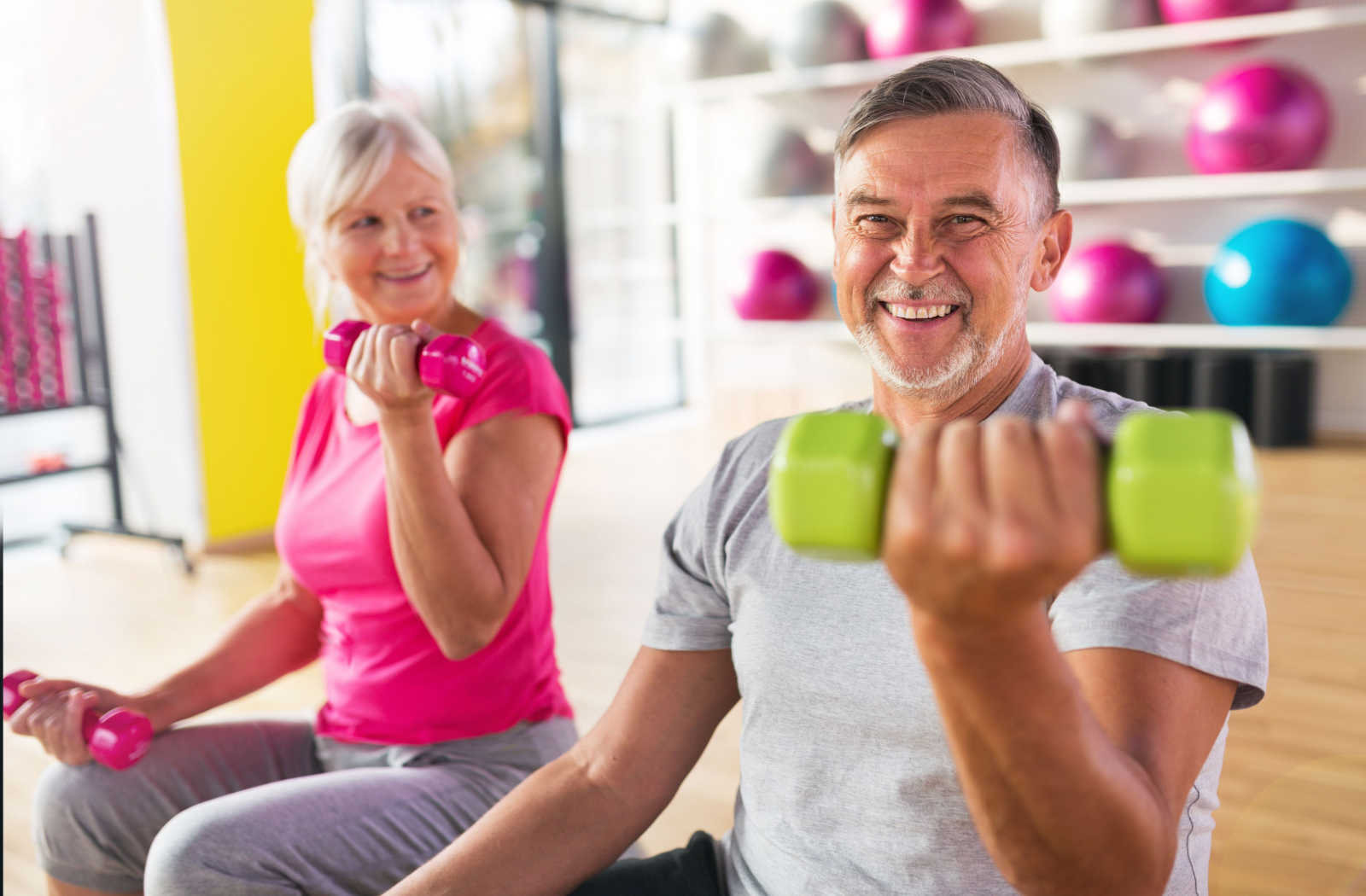 Senior couple exercising together at the gym, using weightlifting equipment and working on their fitness.