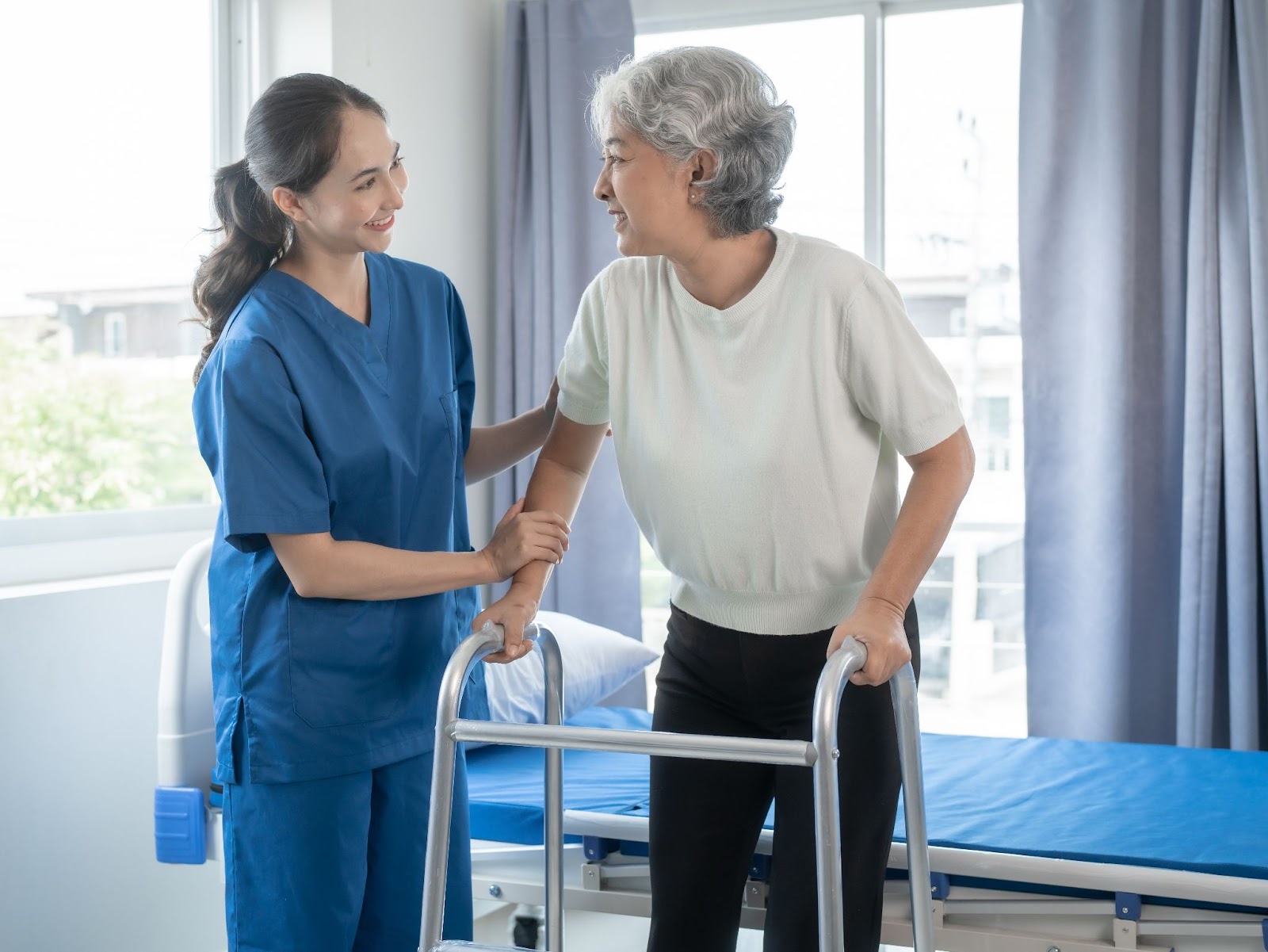 A nurse helping a senior woman with multiple sclerosis using a walker.