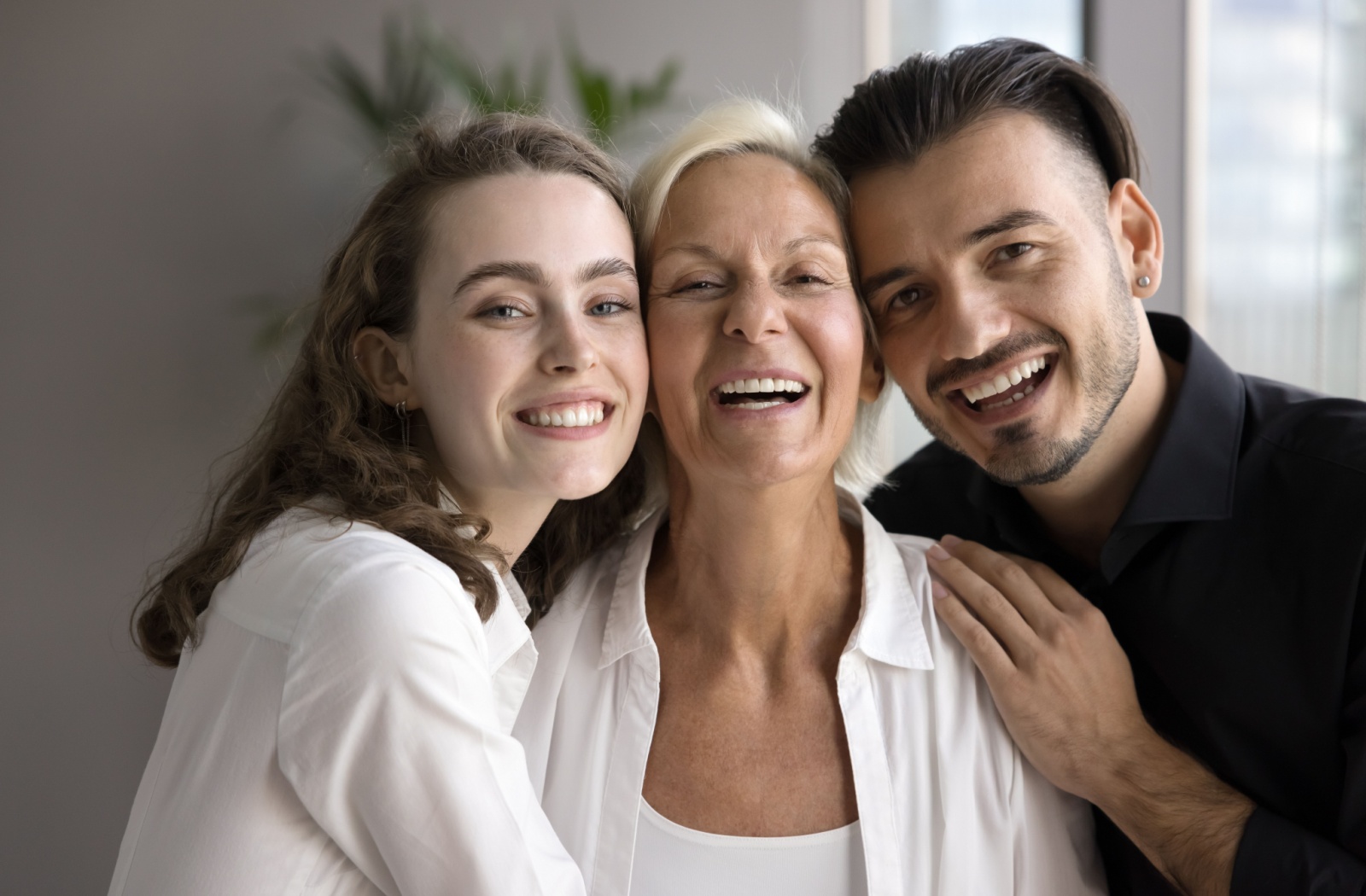 Two siblings caring for their aging parent all smiling to camera.