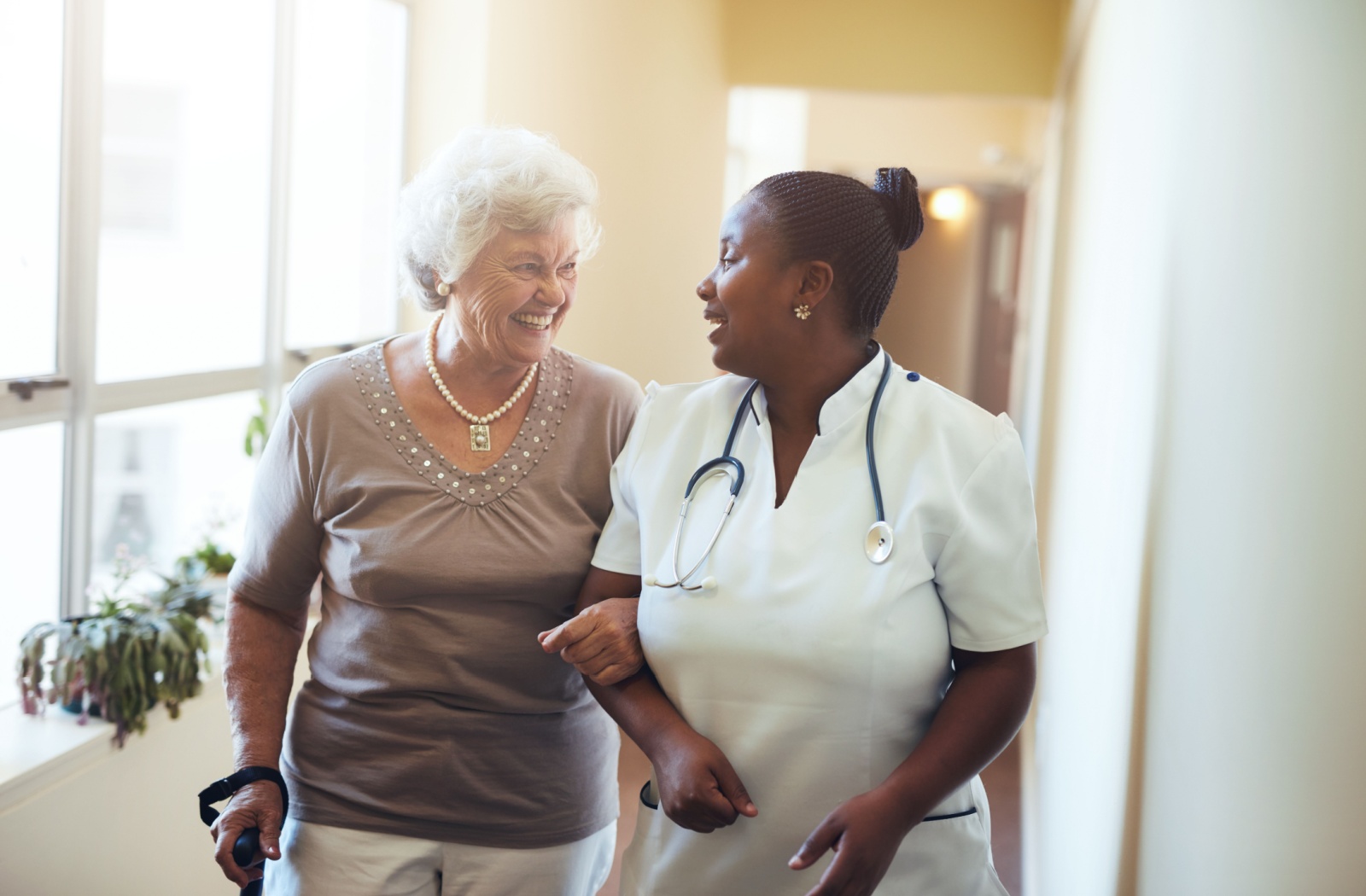A senior person accompanied by a memory care nurse within a senior community.